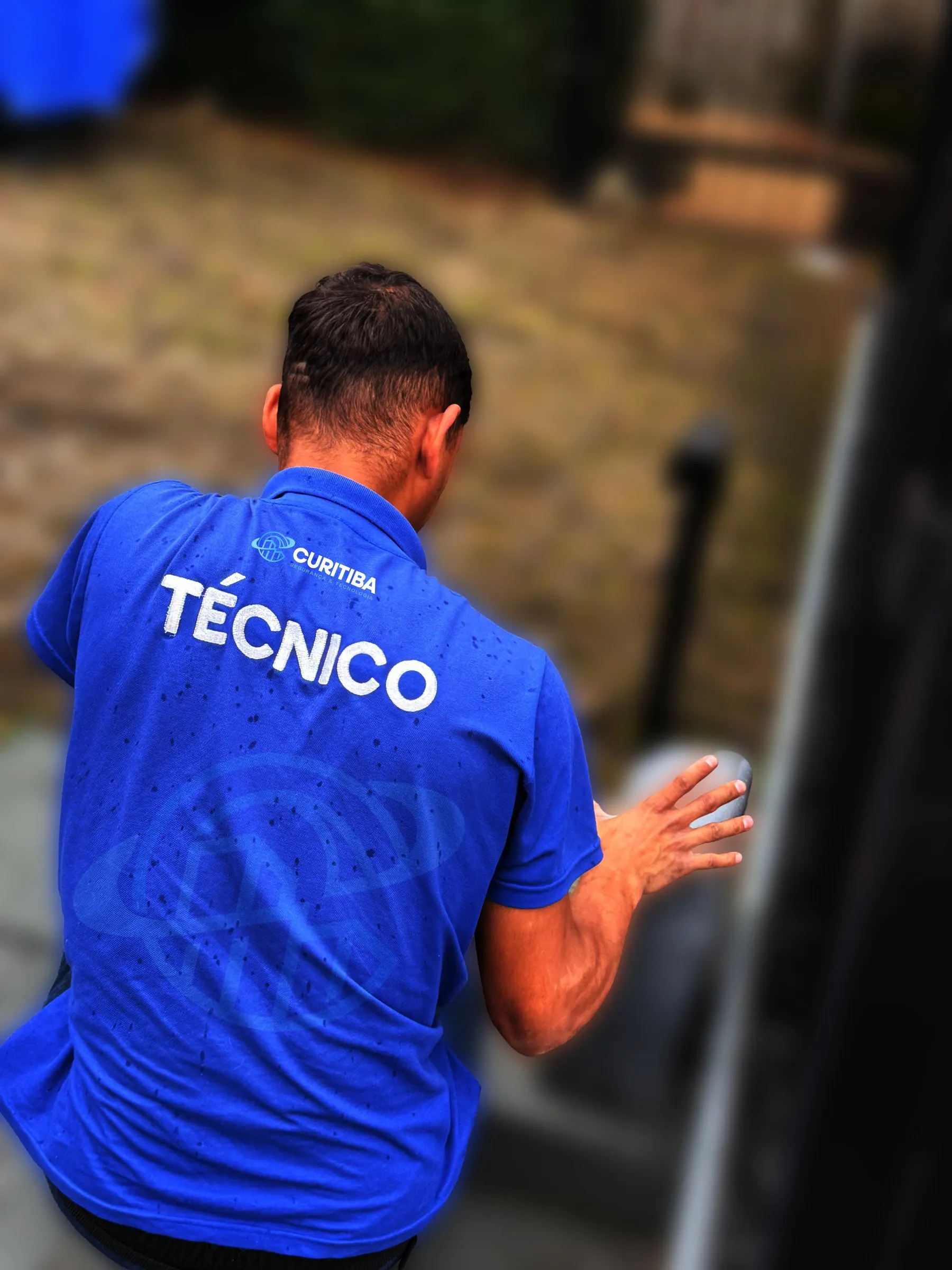 Técnico da Curitiba, com a camisa azul do uniforme, trabalhando num portão